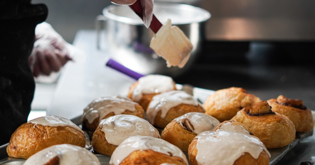 a person is spreading icing on a tray of pastries