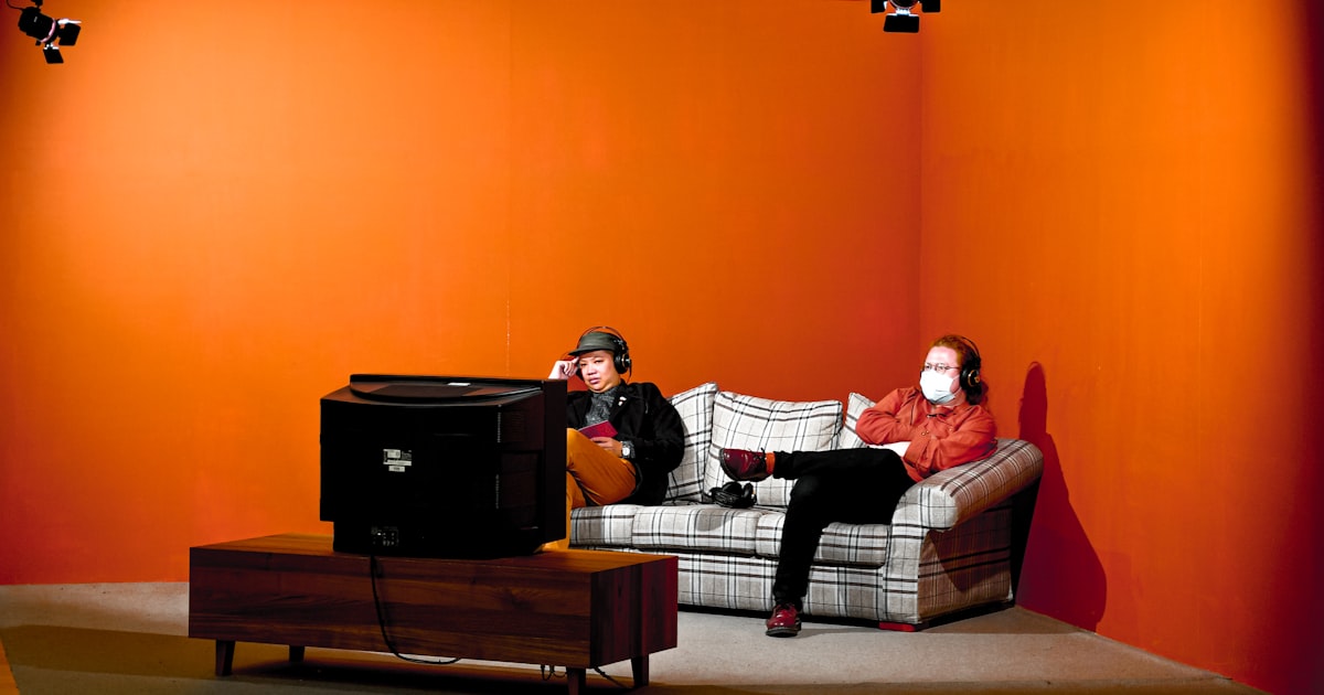 man and woman sitting on brown and white plaid sofa chair