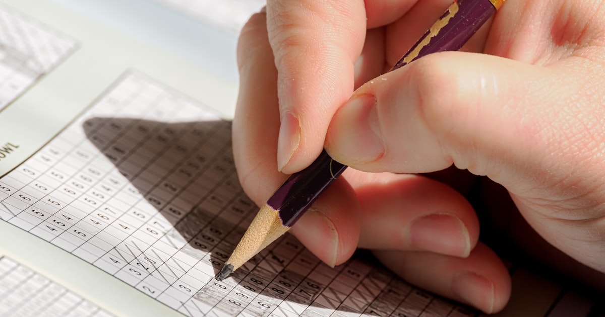 A person holding a pencil and writing on a piece of paper