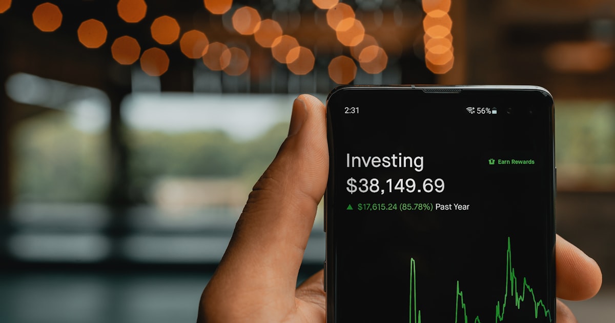 a person holding up a cell phone with a stock chart on it