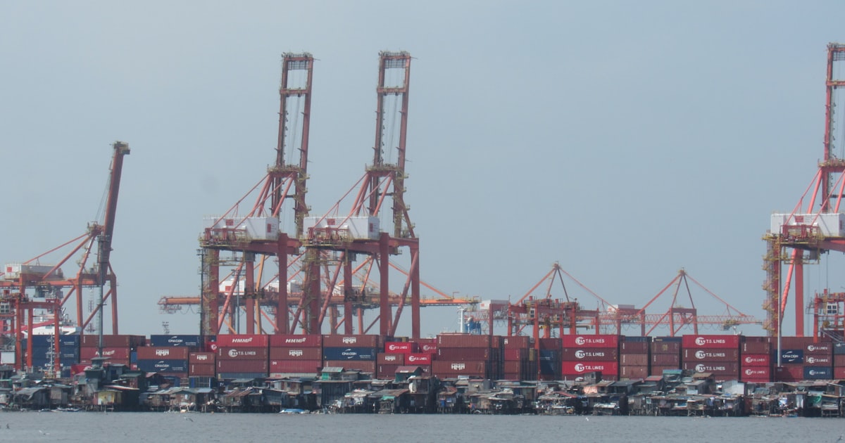 Large cranes and shipping containers at a busy port.