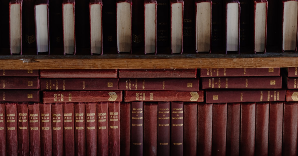 A row of books sitting on top of a wooden shelf