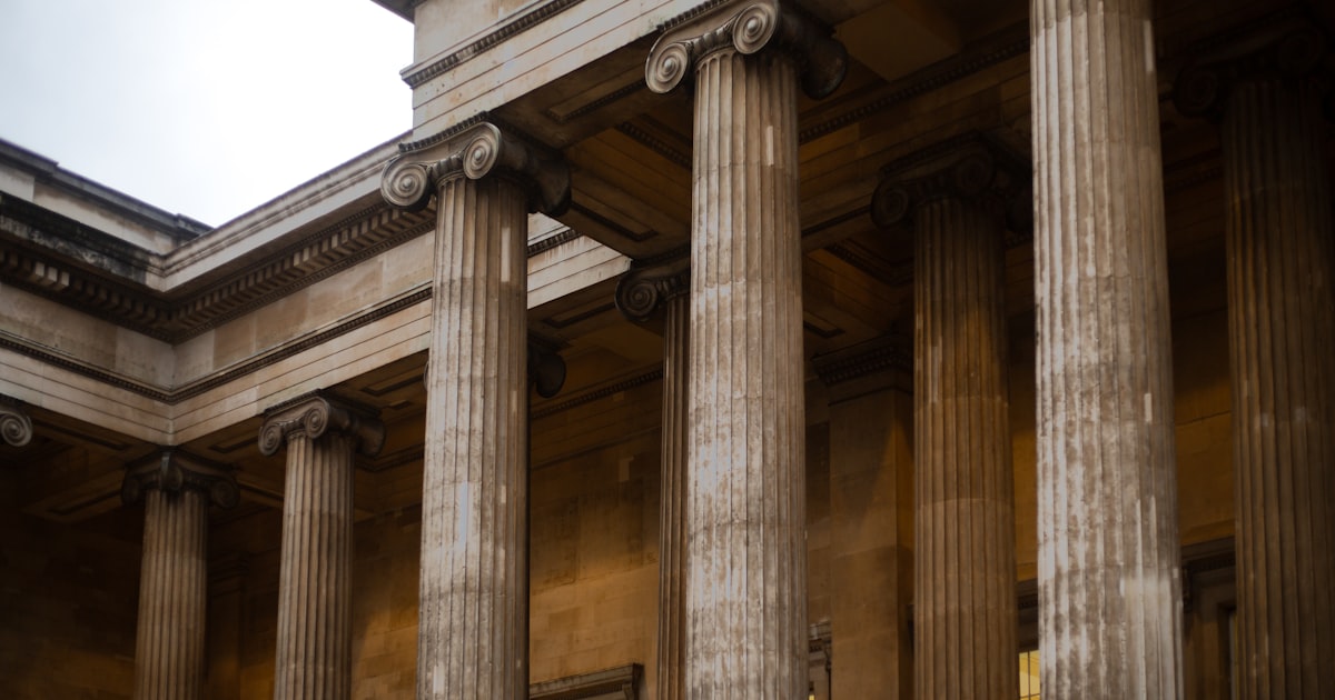 a large building with columns and a clock on the side of it
