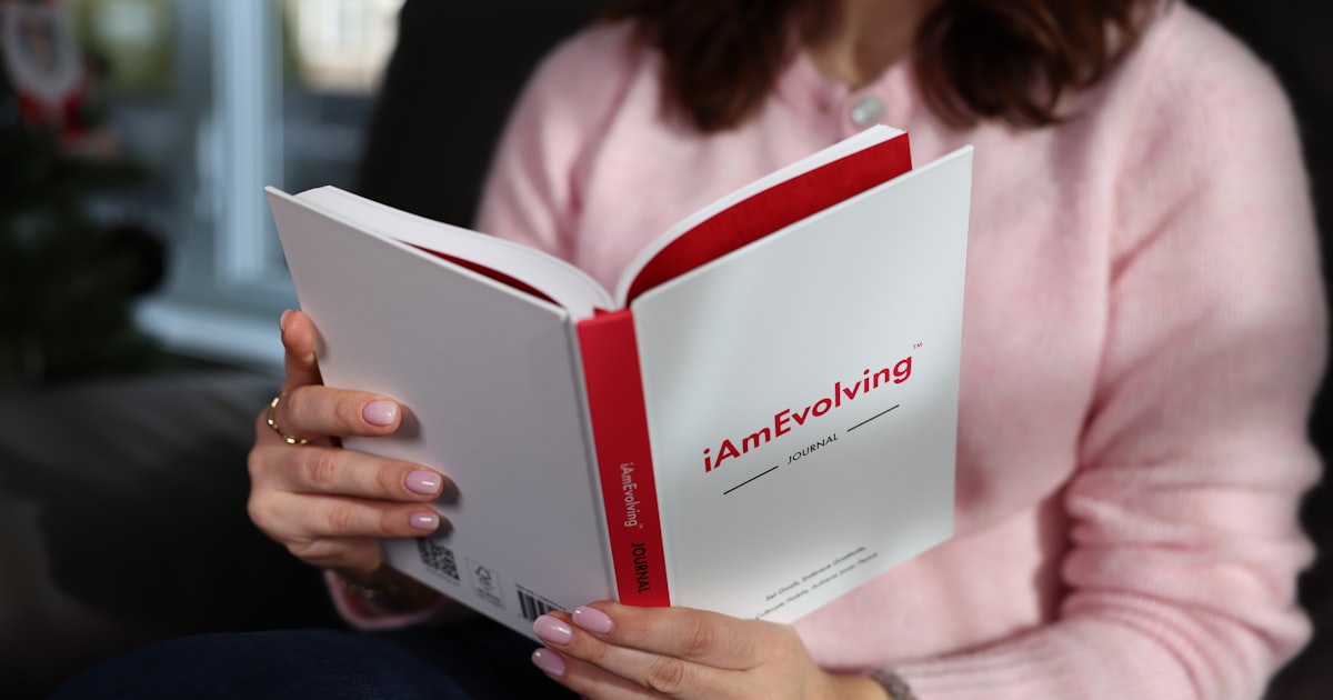 Person in pink sweater reading a white book