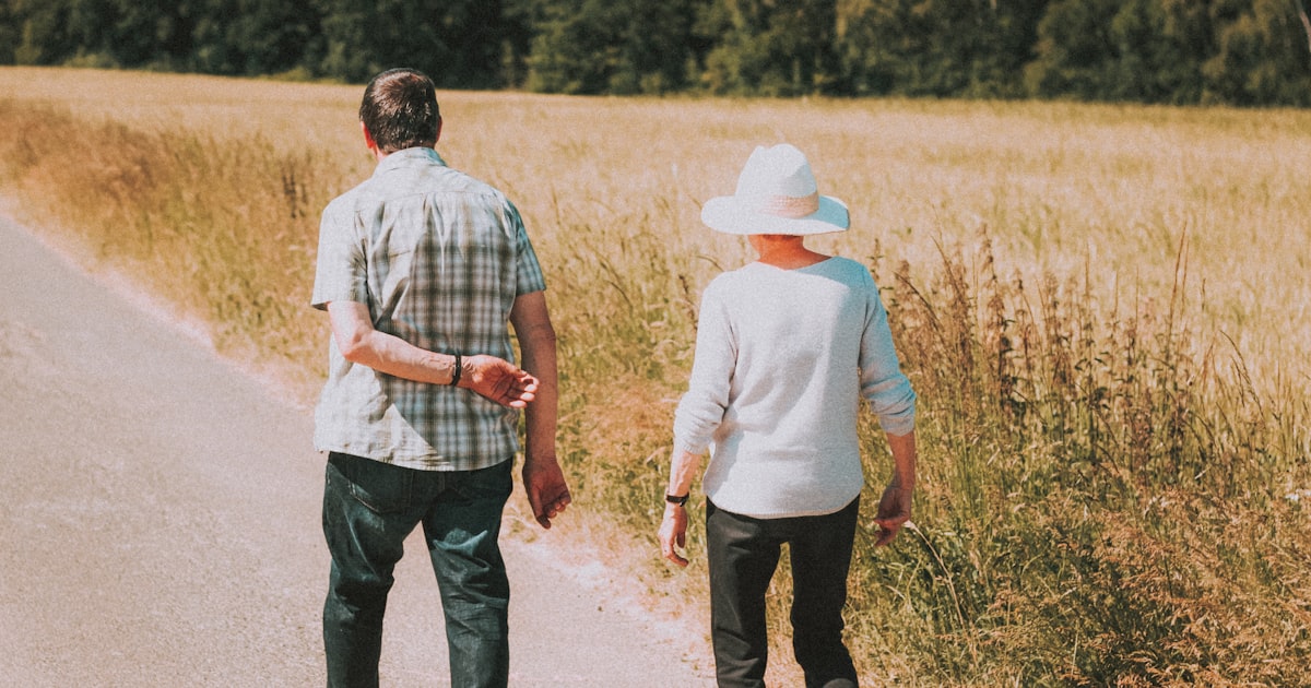 man and woman holding hands while walking on road during daytime