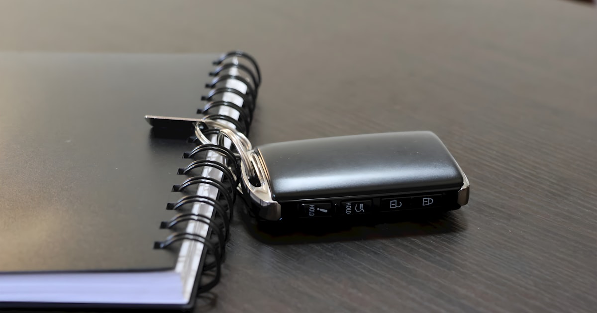 A car key lies next to a notebook.
