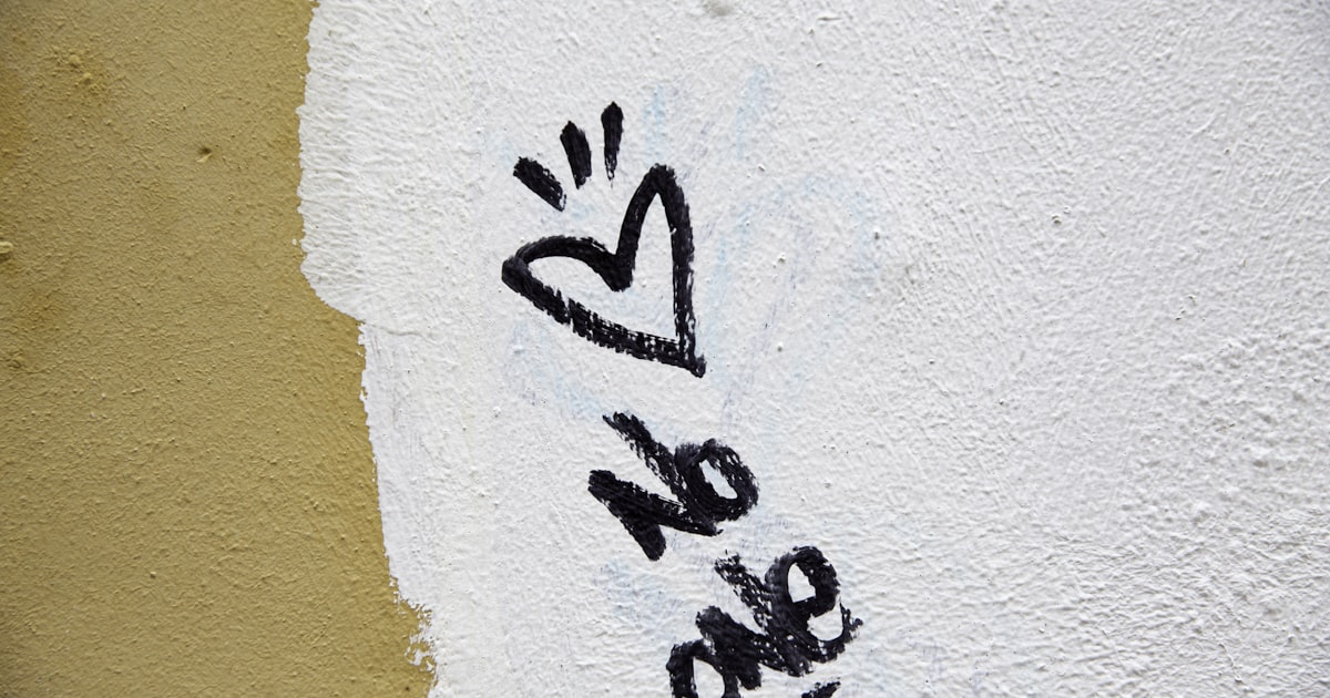 Black graffiti heart and "love" on a white wall.