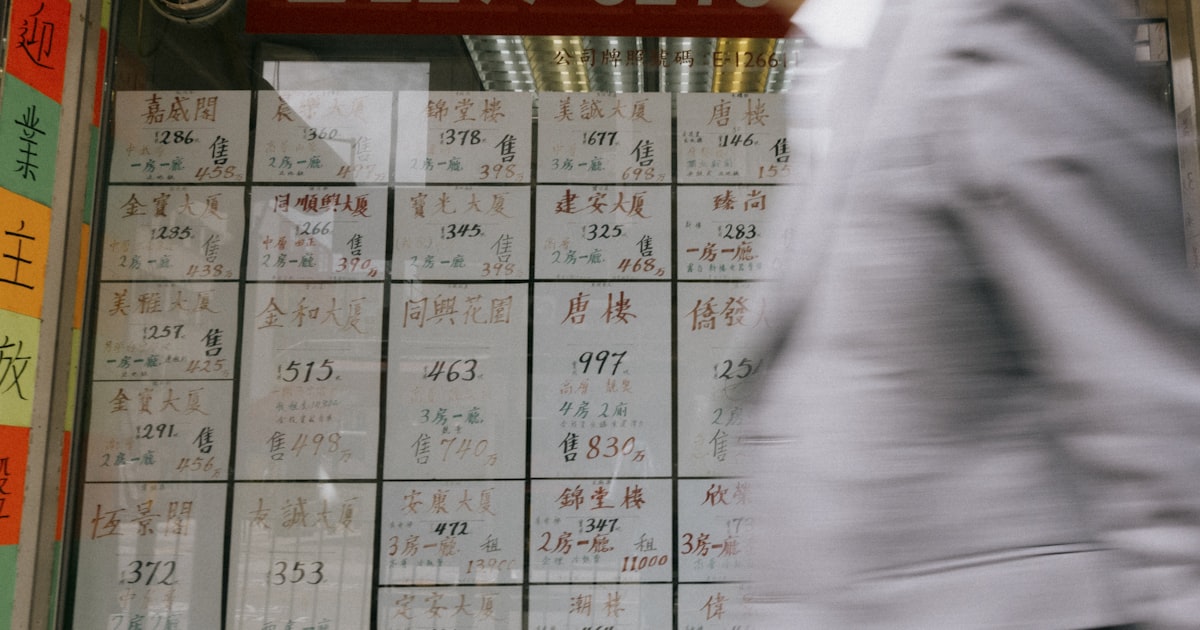 a man in a suit walking past a wall with writing on it