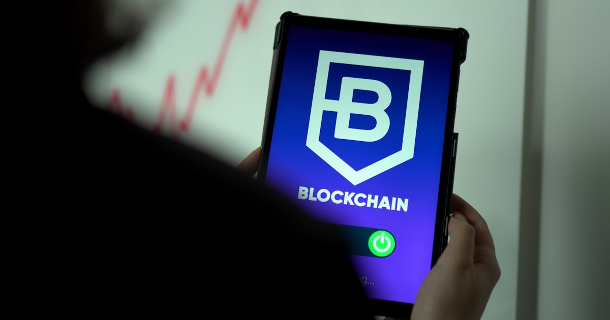 a person holding a cell phone with a blockchain logo on it