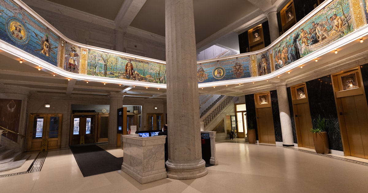 Grand hall with a central pillar and ornate murals.