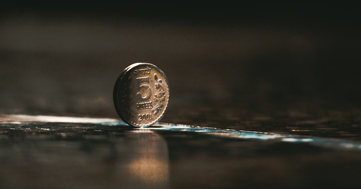silver round coin on brown wooden table