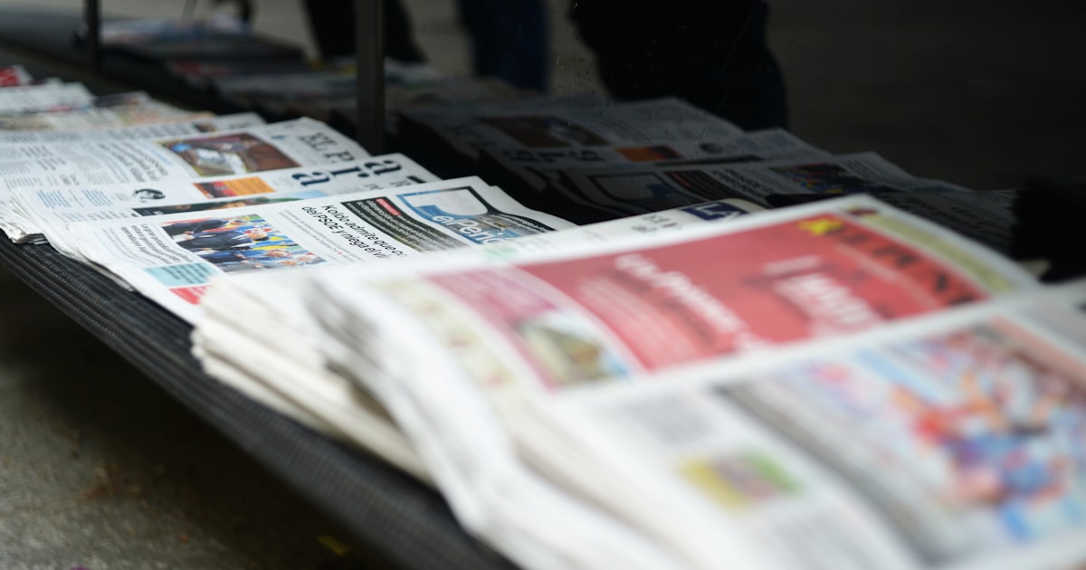 Stack of newspapers on a table outdoors.