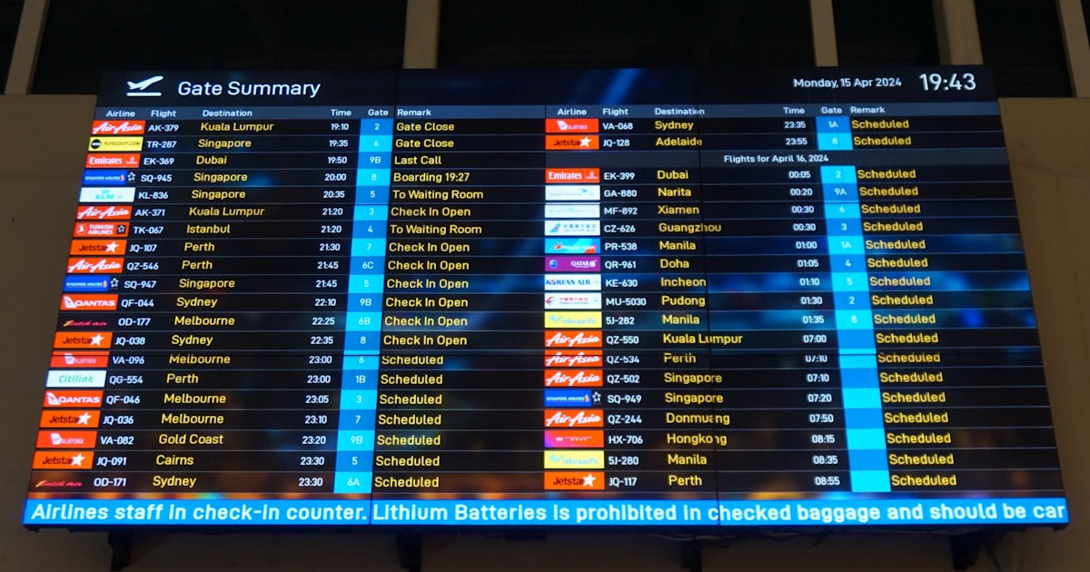 A large screen displaying a flight schedule at an airport