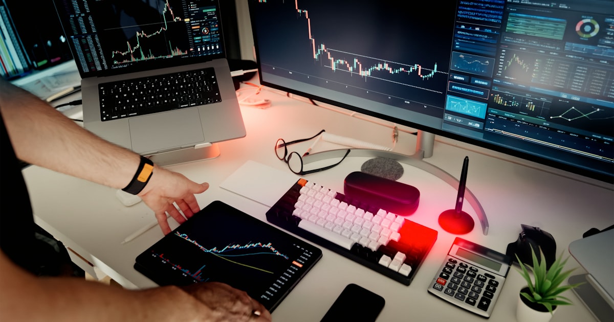 A man sitting at a desk with two monitors and a laptop