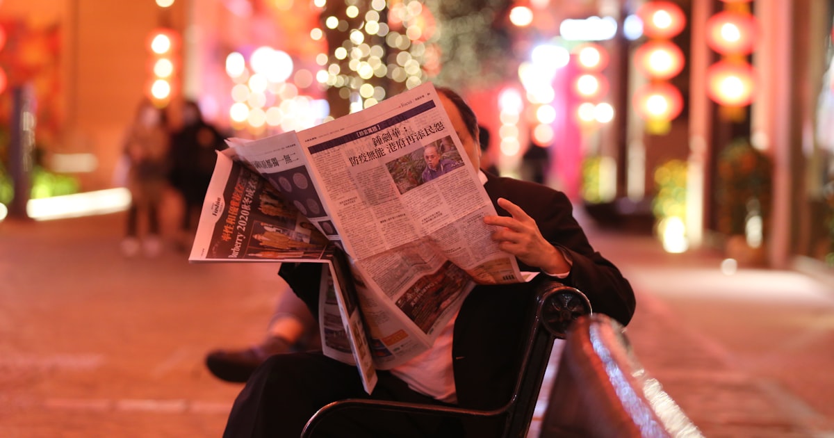 person reading newspaper sitting on chair