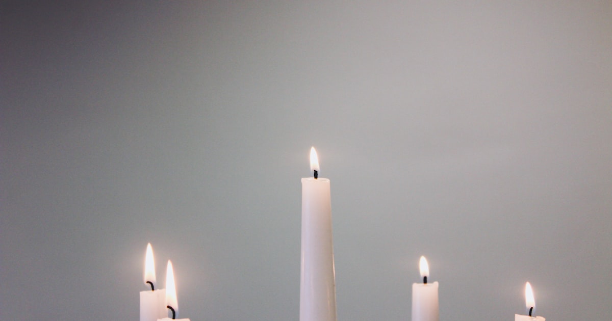five lit white taper candles