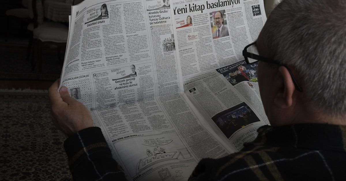 a man reading a newspaper while wearing glasses