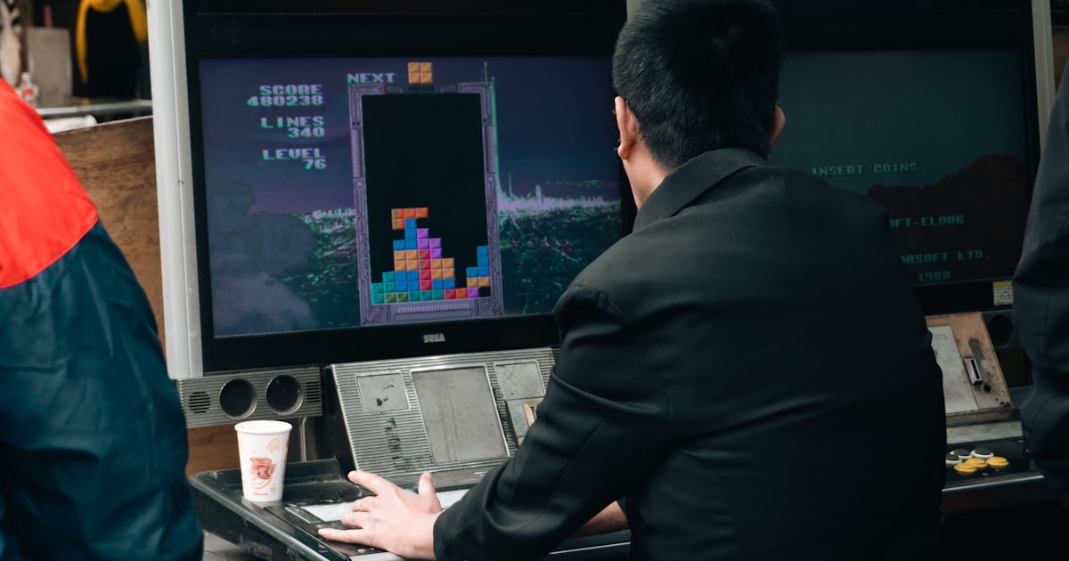 A man plays tetris on a vintage arcade game.