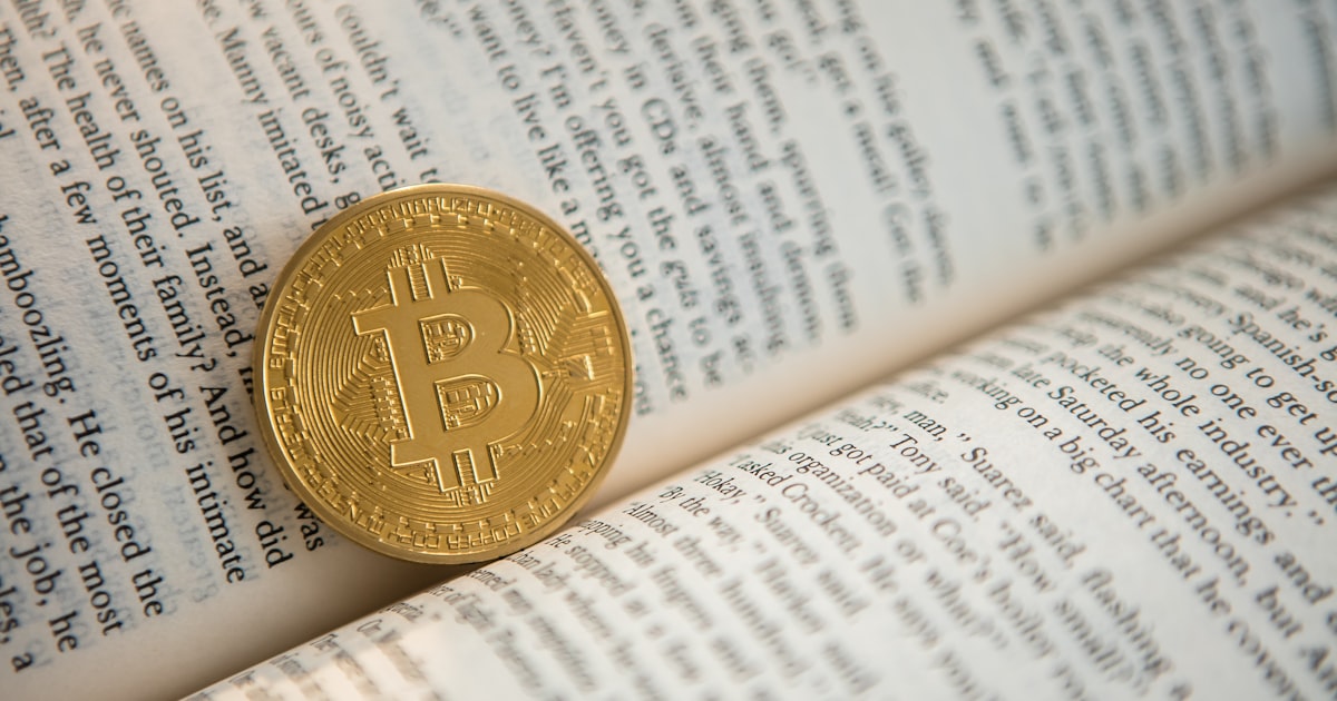gold-colored Bitcoin on book