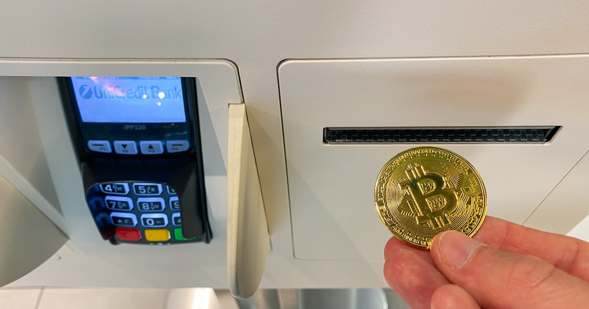 a hand holding a coin in front of a machine