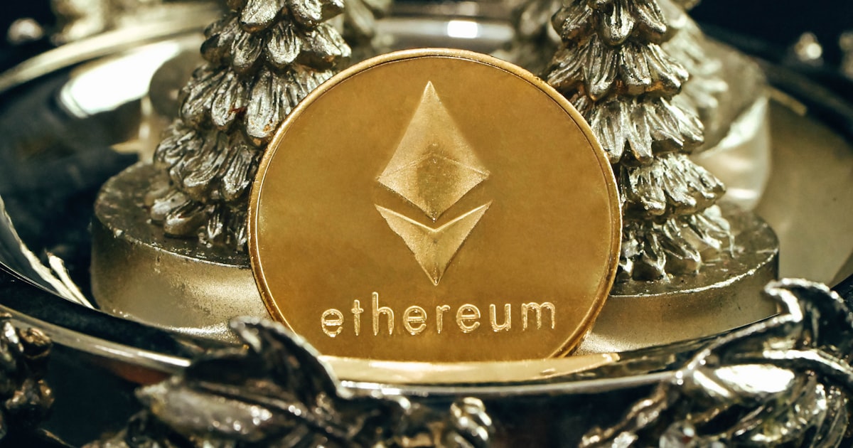 a gold ethereum coin sitting on top of a metal tray