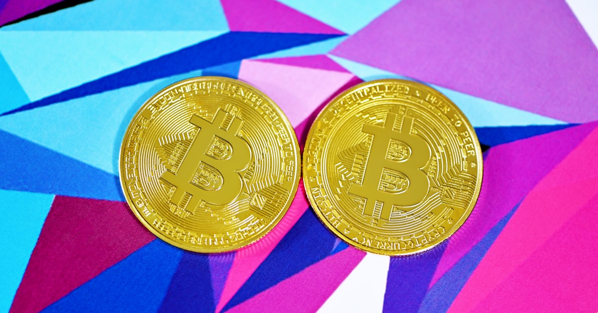 two gold bitcoins sitting side by side on a colorful background