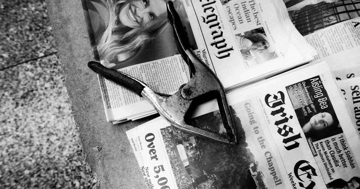 A spring clamp rests on black and white newspapers.