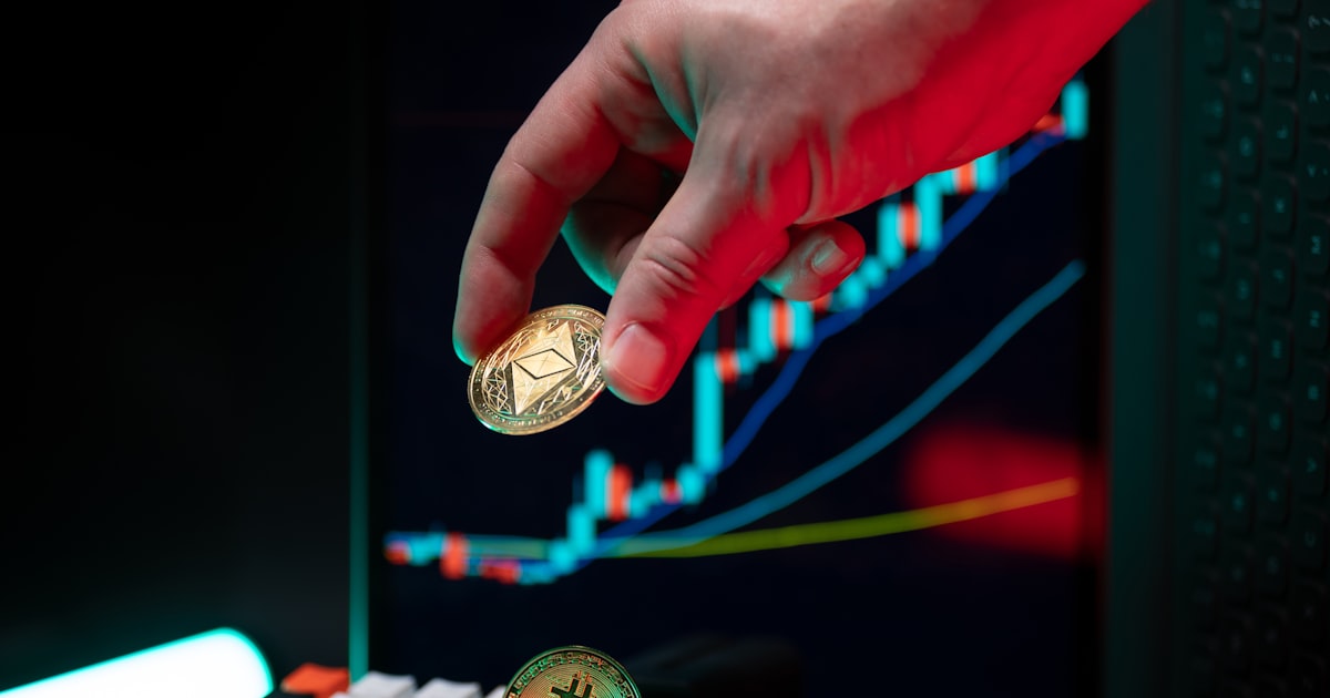 Hand holding ethereum with crypto graphs in background.