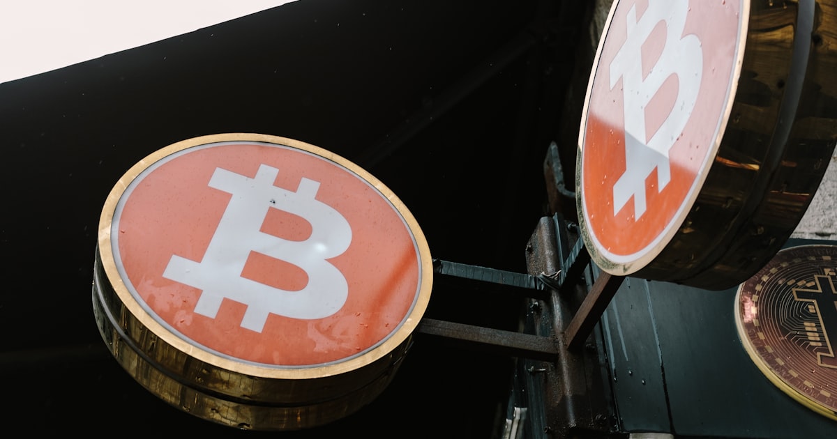 A bitcoin sign hanging from the side of a building