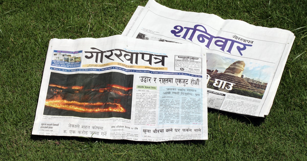 A newspaper laying on top of a lush green field