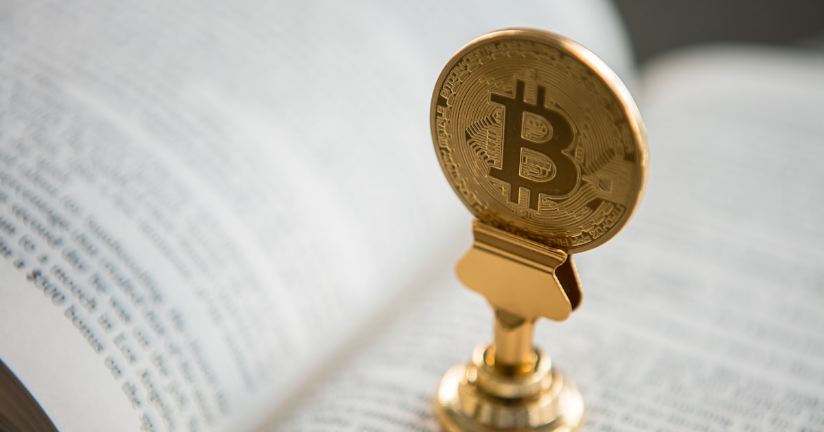 bitcoin on gold stand on top of book