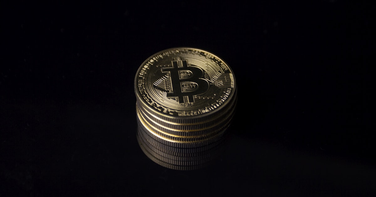 a stack of gold bitcoins on a black background