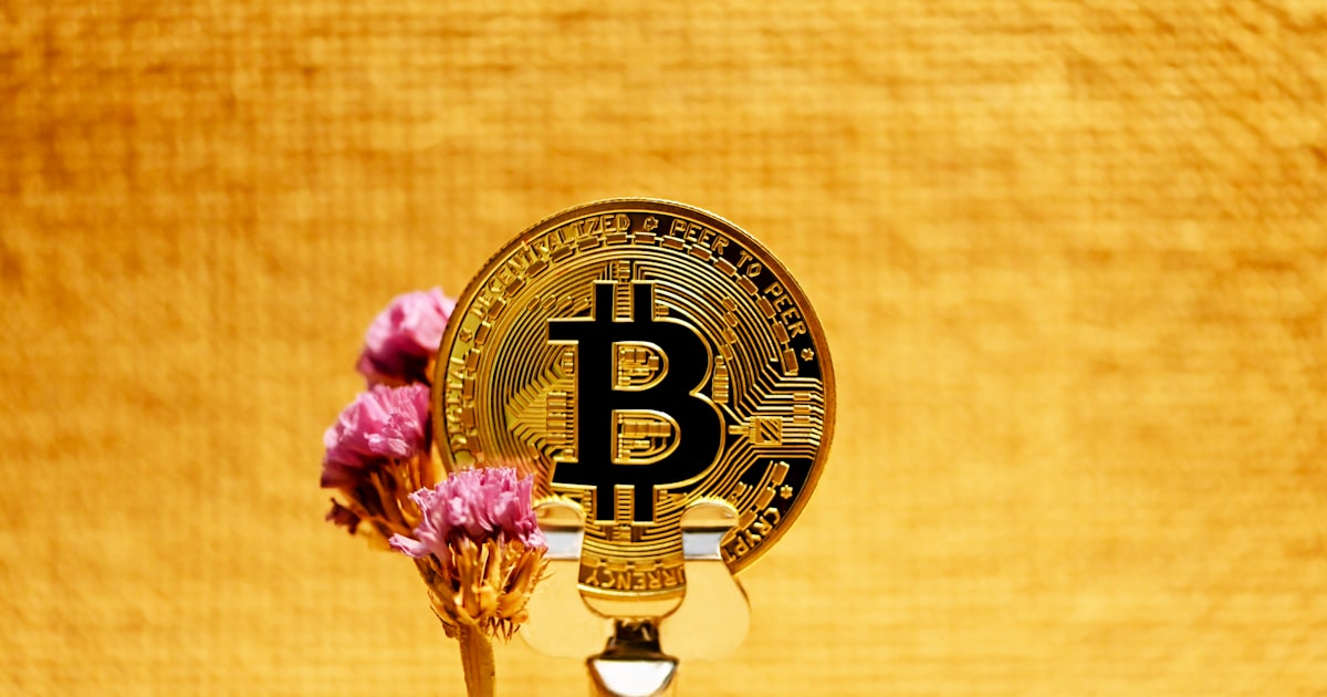 a bitcoin on top of a gold plate with pink flowers