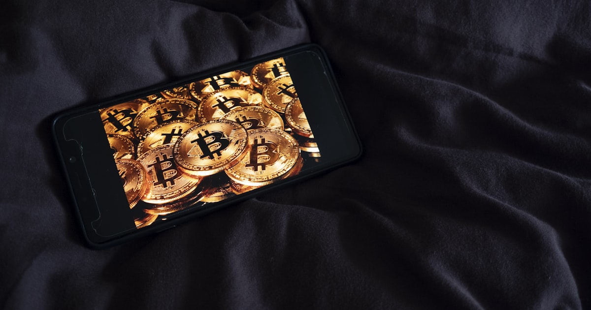 a cell phone sitting on top of a bed covered in gold coins