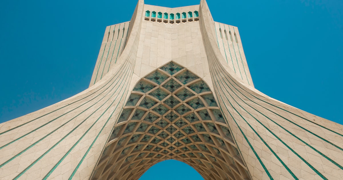 a tall building with a curved roof with Azadi Tower in the background