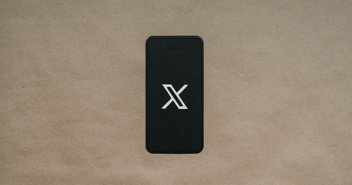 a black cell phone laying on top of a brown surface