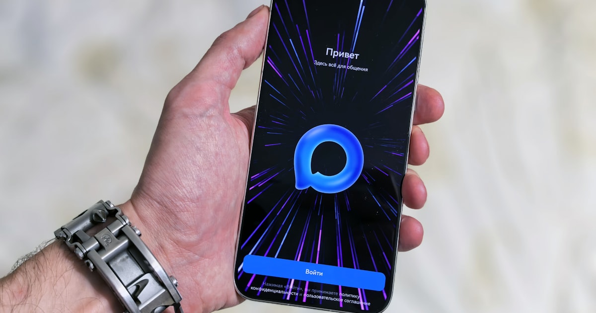 Hand holding smartphone with glowing purple abstract background.