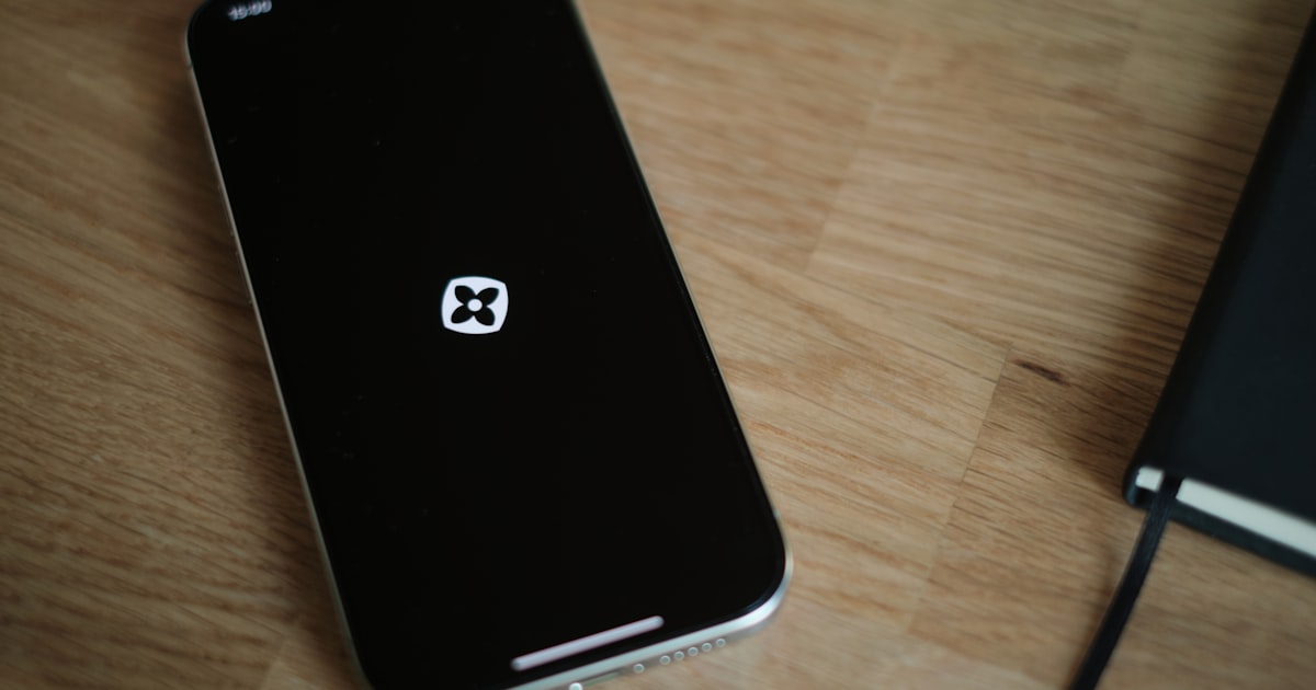 A black cell phone sitting on top of a wooden table