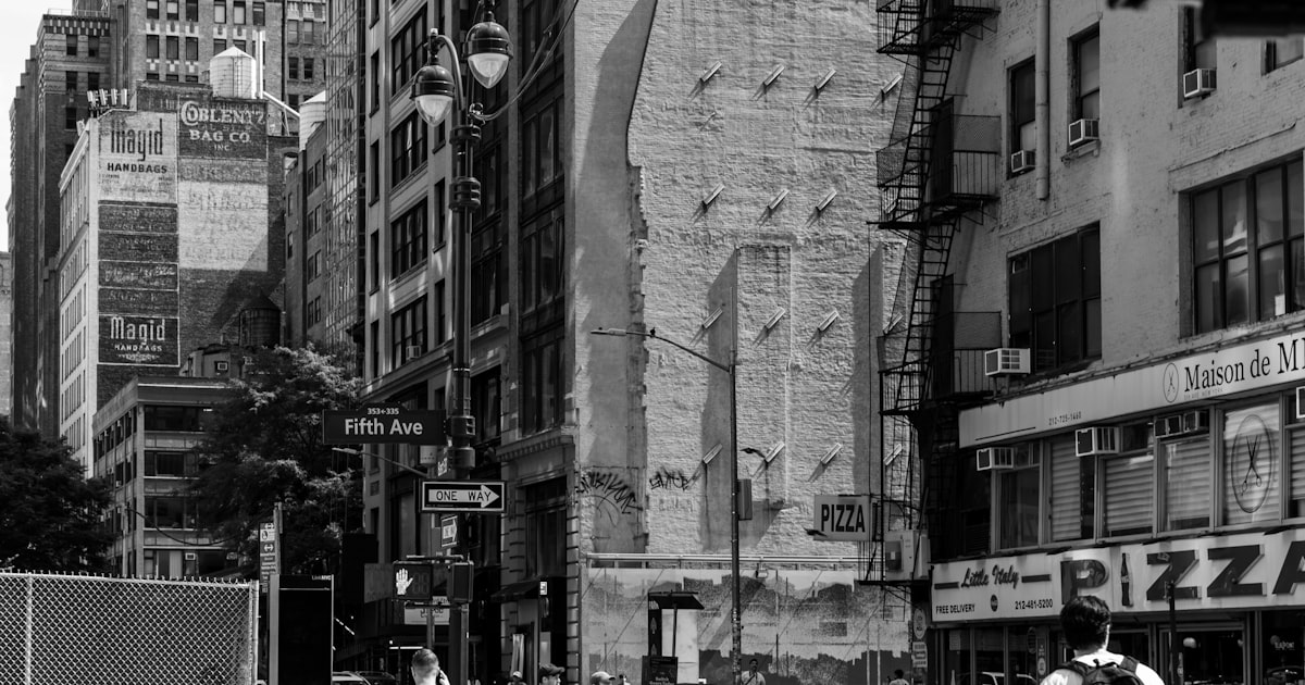 Black and white street scene with buildings and people.