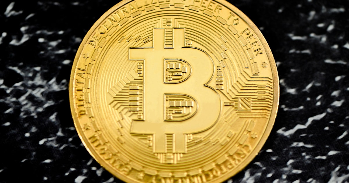 a gold bit coin sitting on top of a black table