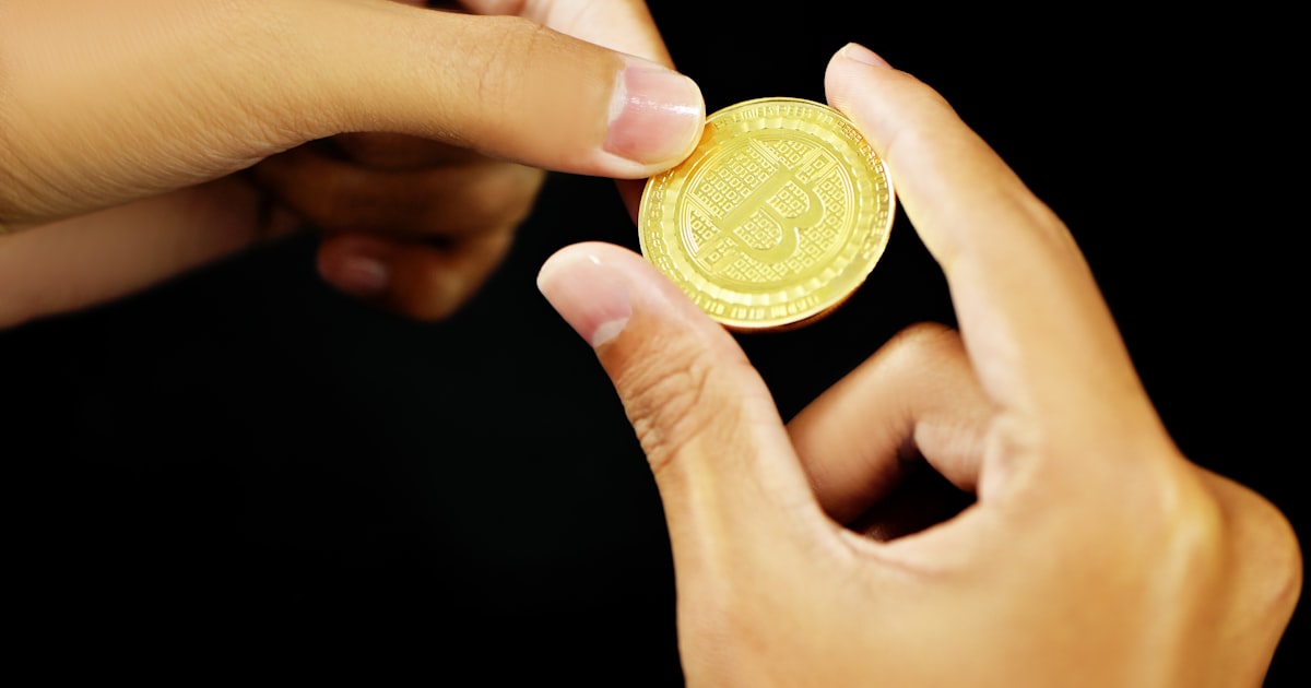 gold round coin on persons hand