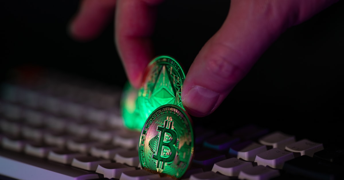Hand placing glowing crypto coins on a keyboard.