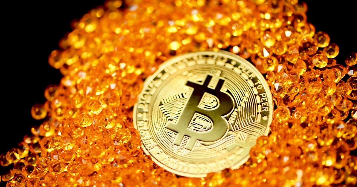 a bitcoin sitting on top of a pile of gold beads