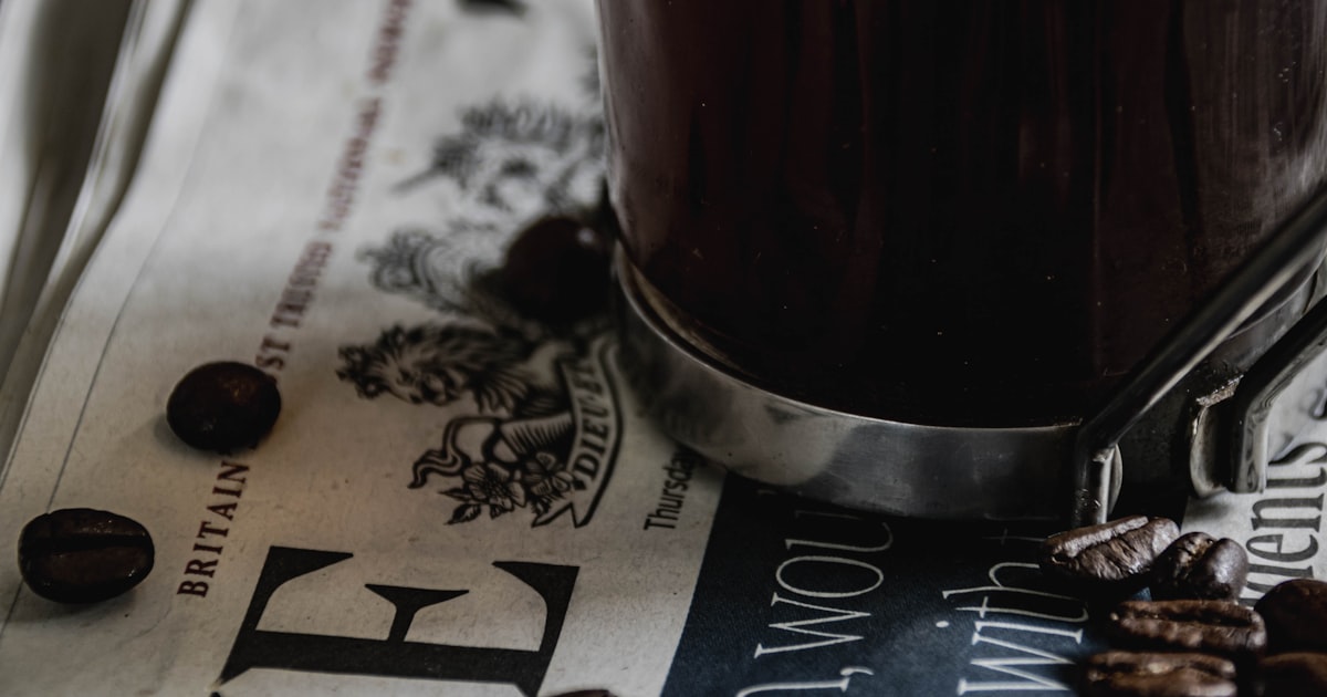 a cup of coffee sitting on top of a newspaper