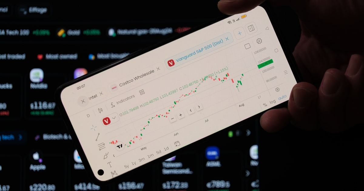 A person holding a cell phone in front of a laptop