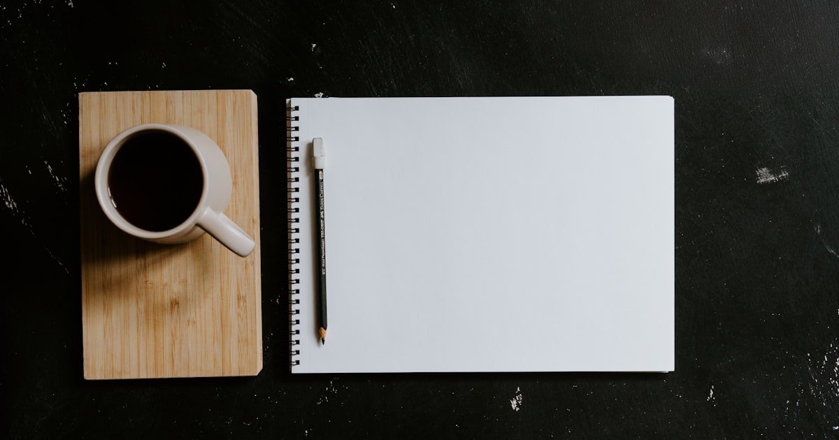A cup of coffee and notebook with a pencil