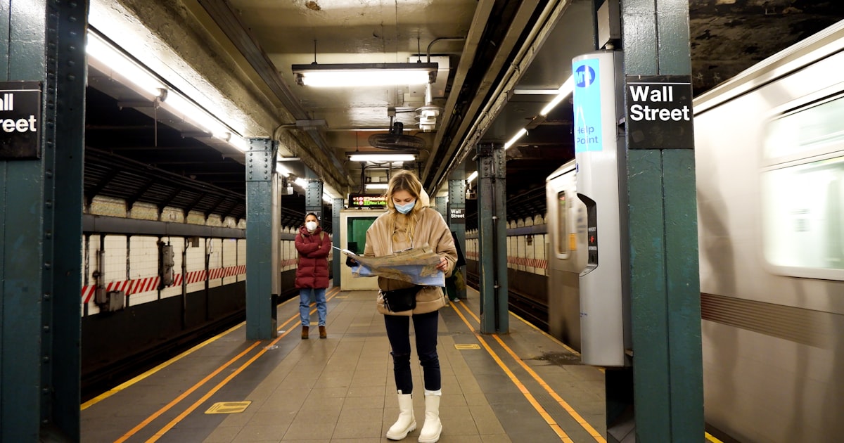woman in brown coat standing on train station