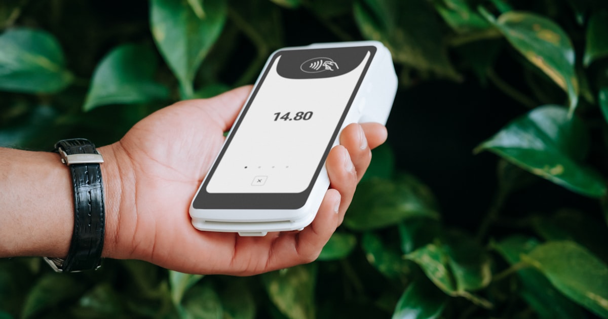 A hand holds a payment terminal.