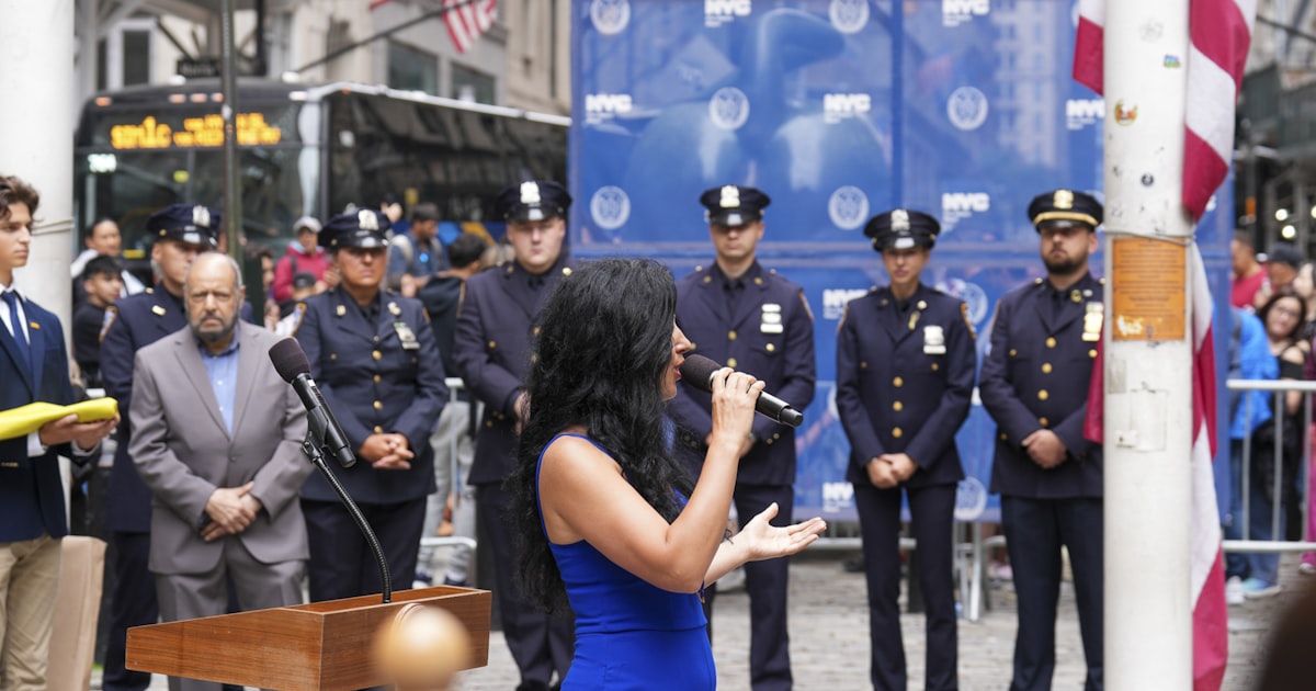 Woman speaks at podium with police officers behind her