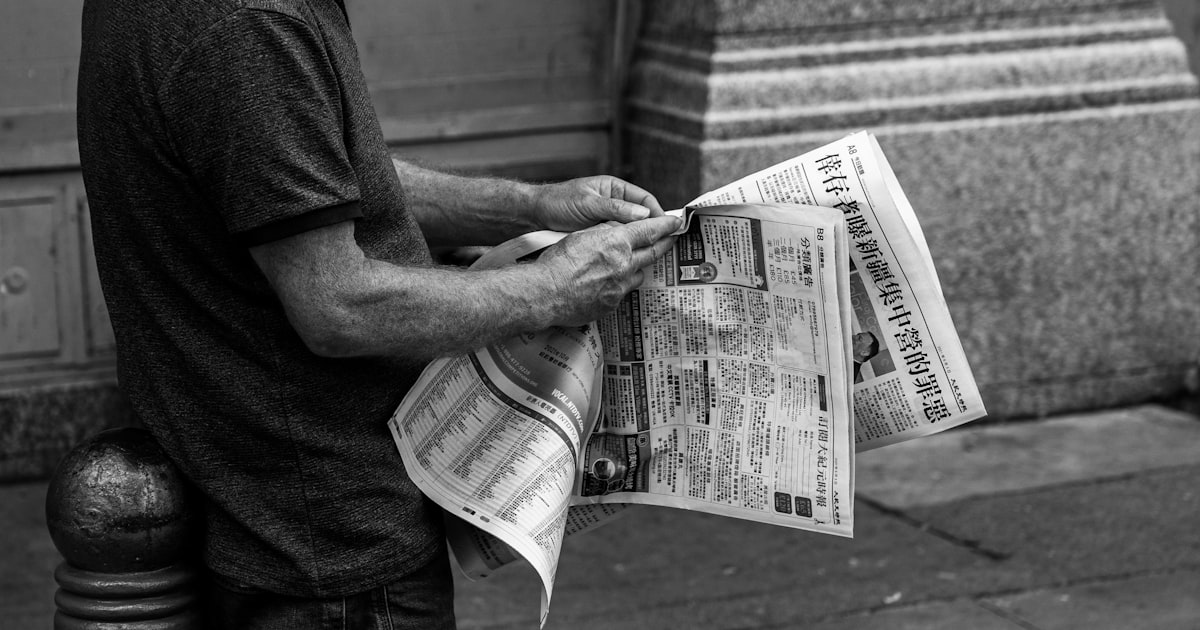 grayscale photo of man holding newspaper